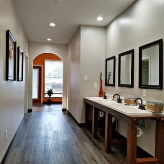 A modern bathroom hallway featuring dual sinks, stylish mirrors, and elegant lighting.
