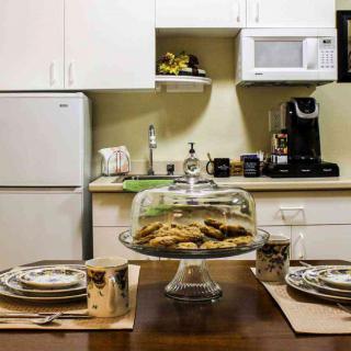 A cozy kitchen setup with freshly baked cookies on a cake stand and a beautifully arranged dining table.