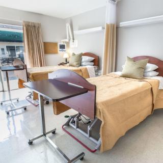 A hospital room with two neatly made beds and medical equipment.