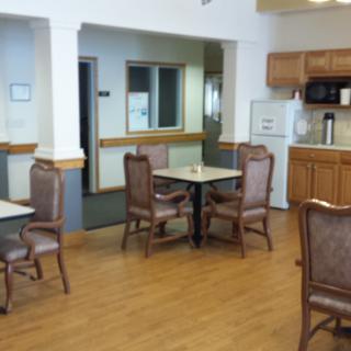 A dining area with tables and chairs next to a kitchen space.