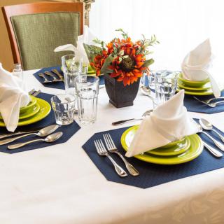 A beautifully arranged dining table with folded napkins, colorful plates, and a floral centerpiece.