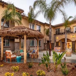 A beautiful tropical-themed house exterior with palm trees and a cozy outdoor seating area.
