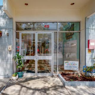 The inviting entrance of a modern building, showcasing glass doors and potted plants.