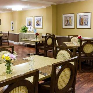 A cozy dining room with elegantly set tables featuring flowers and framed artwork on the walls.