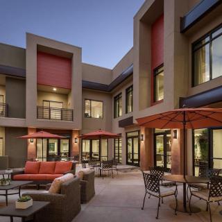A modern residential courtyard with outdoor seating and patio umbrellas at dusk.