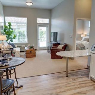A modern apartment with a well-lit living room and adjoining bedroom.