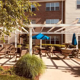 A cozy outdoor patio area with pergola and umbrellas, surrounded by apartment buildings.