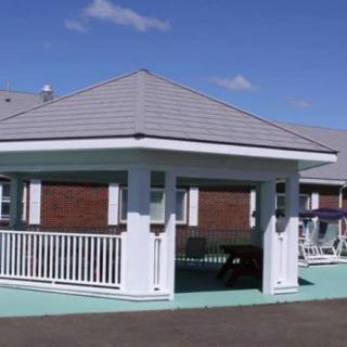 An outdoor pavilion with a pitched roof and white railings on a sunny day.