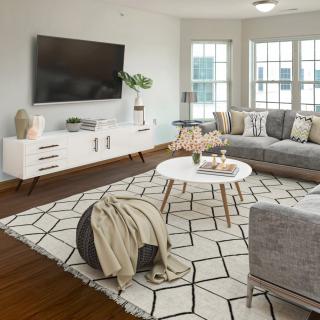 A modern living room featuring a large gray sofa, geometric rug, and sleek white furniture.