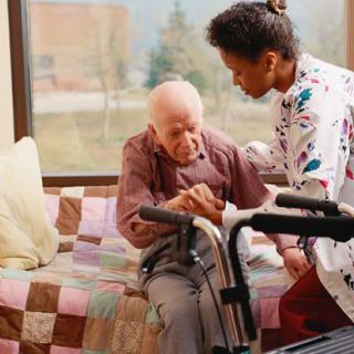 A caregiver assisting an elderly person with a walker in a home setting.