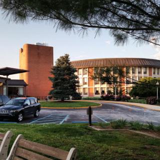 A view of a hotel with surrounding greenery and parking area.