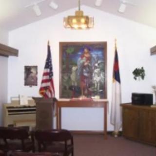 Interior view of a small chapel featuring flags and religious artwork.