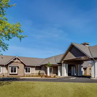 A modern residential building with a sloped roof and landscaped surroundings under a clear sky.