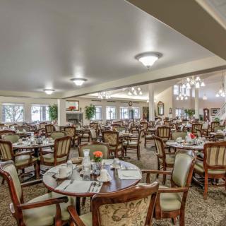 A spacious and elegantly designed dining room with multiple tables and chairs set for service.
