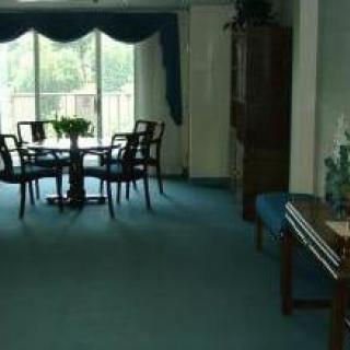 A dining room with a table and chairs in front of large windows with curtains.