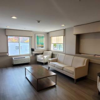 A modern living room with beige sofas and a coffee table, illuminated by natural light from large windows.