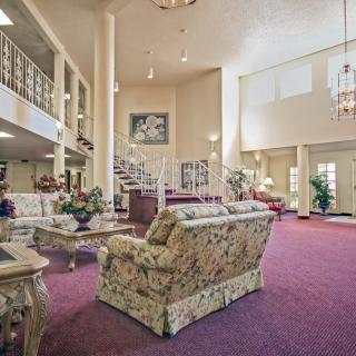 A spacious living room interior with elegant furniture, a grand staircase, and a chandelier.
