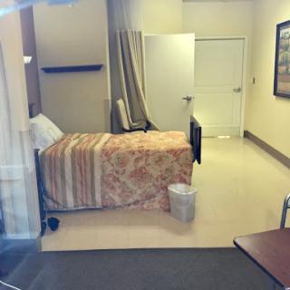 A view of a hospital patient room, featuring a bed and minimal furnishings.