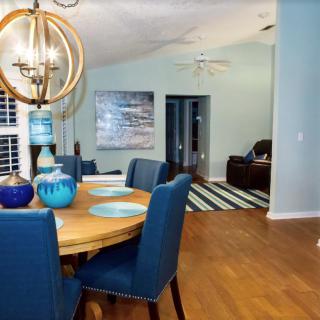 A modern dining room with blue chairs and a stylish chandelier, featuring a cozy open space and wooden floors.
