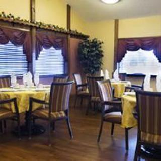 A cozy dining room with elegantly set tables and striped chairs, featuring decorative curtains.