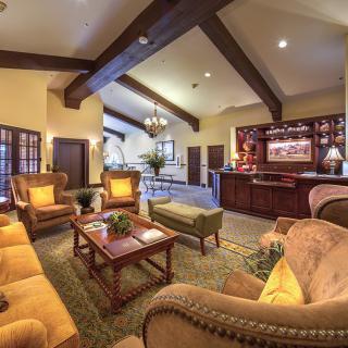 A cozy living room featuring warm lighting, comfortable seating, and elegant wooden beams.