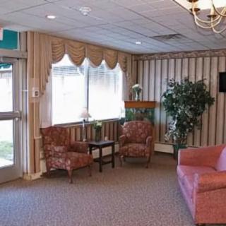 A cozy living room interior with sofas, chairs, and large windows.