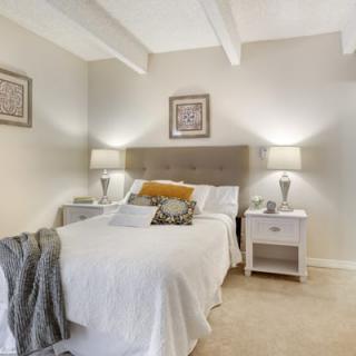 A cozy and modern bedroom featuring a neatly made bed, bedside tables, and elegant lamps.