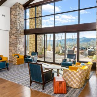 A modern living room with large windows offering a view of the mountains, featuring stylish furniture and ample natural light.