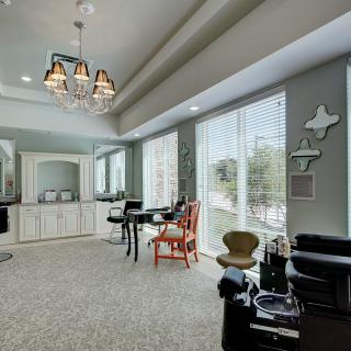 A modern salon interior with stylish chairs, large mirrors, and elegant chandeliers.