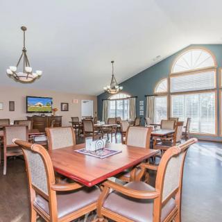 A spacious dining room with wooden tables and chairs, featuring large windows that allow natural light to fill the space.