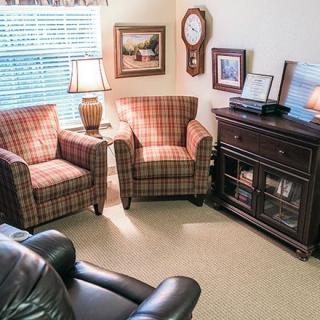 A cozy living room with plaid chairs, a lamp, and decorative elements.