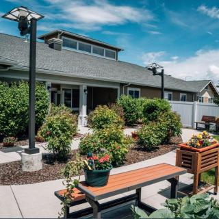 A beautifully landscaped garden with benches and vibrant plants under a clear blue sky.