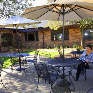 Outdoor patio area with tables, chairs, and umbrellas near a brick building.