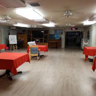 A spacious indoor area set up with red tablecloths, ready for an event.