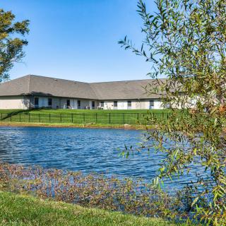 A peaceful view of a building by a pond surrounded by greenery.