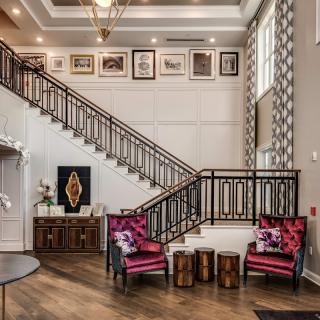 Elegant living space with a staircase, vibrant seating area, and framed artwork.