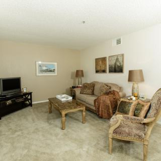 A cozy living room with a sofa, armchair, coffee table, and a TV.