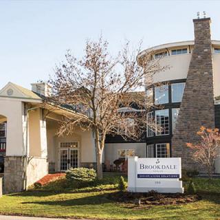 A hotel building featuring modern architecture with a stone chimney and surrounding trees.
