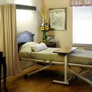 A hospital room with a bed and medical equipment, decorated with flowers and artwork.