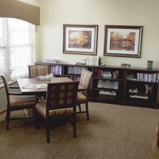 A cozy living room with a table and chairs, decorated with bookshelves and artwork on the walls.