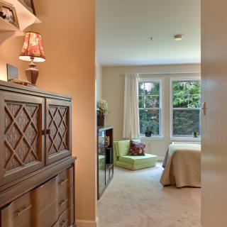 A cozy bedroom with natural light streaming in through a large window, showcasing elegant furniture and decor.