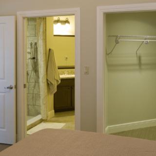 A modern bedroom with an open view of the bathroom and closet.