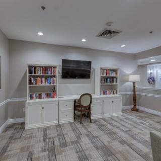 A cozy library room with bookshelves, a chair, and a television.