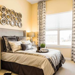 A cozy and modern bedroom with stylish bedding, wall art, and patterned curtains.