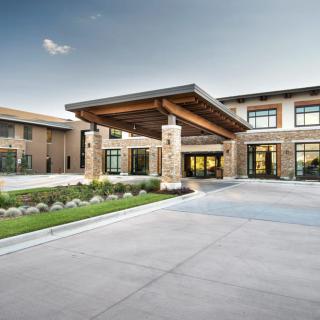 A modern building with a prominent entrance featuring wooden beams and glass windows.