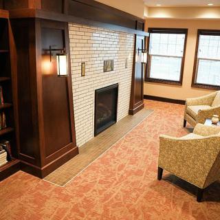A cozy living room featuring a brick fireplace, armchairs, and warm lighting.