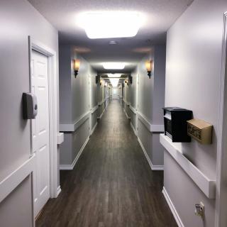 A long, well-lit hallway with wooden flooring and multiple doors along the sides.