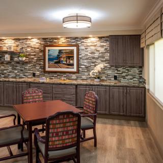 A modern dining room with a stylish table and chairs set, featuring a stone accent wall, artwork, and ambient lighting.