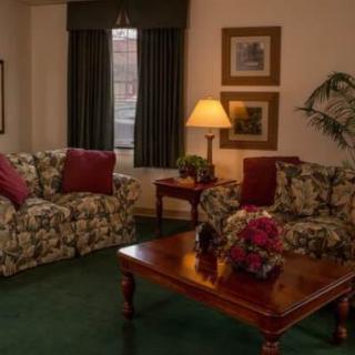 A cozy living room with floral patterned sofas, a wooden coffee table, and warm ambient lighting.