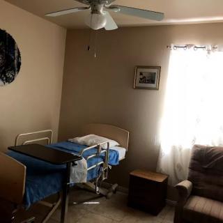A bedroom with a hospital bed, sofa, and window with natural light.